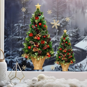 Mini green Christmas tree with red ornaments and golden base in a snowy window setting