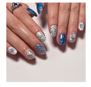 Detail of short round press-on nails with blue marble design, silver moon and star accents