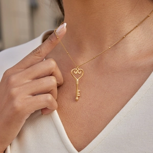 Collier de luxe en acier doré avec pendentif clé en cœur sur la clavicule du mannequin