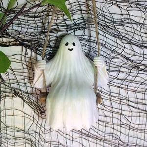 Detail of a white ghost figurine sitting on a rope swing for Halloween tree decoration