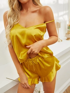 Detail of glossy yellow satin camisole and ruffle shorts sleepwear set for women