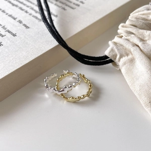 Artistic wavy minimalist silver and gold rings on rustic linen background