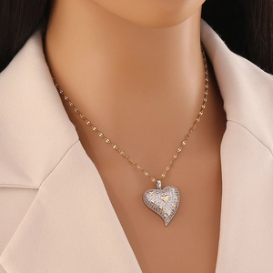 Vue détaillée d'un collier avec pendentif cœur bicolore serti de cristaux sur chaîne dorée