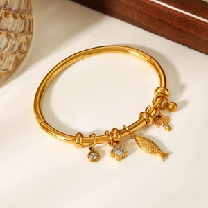 Détail d'un bracelet en acier doré 18 carats avec breloques poisson, étoile et palmier