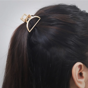 Side view of golden geometric metal hair claw clip fixing a high ponytail for women