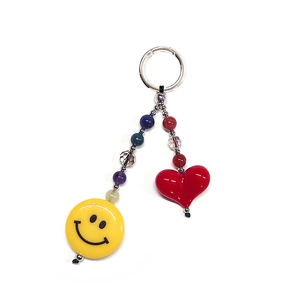 Close-up of beaded keychain with yellow smiley face and red heart charms on silver ring