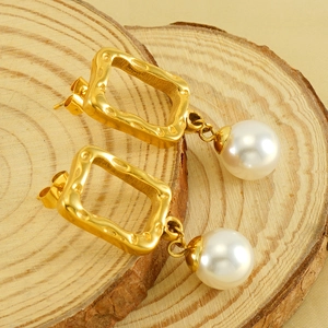Gold hammered square stud earrings with pearls on a wooden display for women