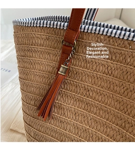 Detail of woven straw tote bag with brown leather tassel and blue striped fabric lining