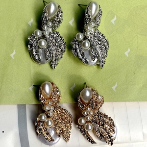 Detail of vintage metal leaf earrings with large pearl accents and colorful oil drop finish