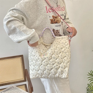 Close-up of quilted floral tote bag with purple accents and adjustable shoulder strap