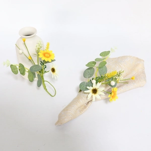 Detail of eucalyptus leaf and daisy napkin ring with pearls on a white ceramic vase