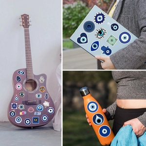 Blue Evil Eye and Hamsa stickers applied on a guitar, laptop and water bottle