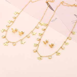 Golden butterfly and eye charm necklaces with matching stud earrings on pink background