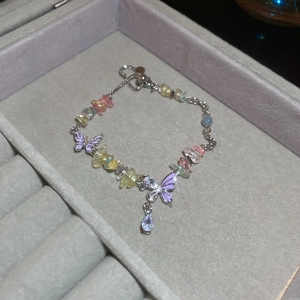 Detail of colorful stone butterfly necklace with purple enamel and crystal teardrop charm