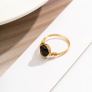 Detailed close-up of handmade gold wire-wrapped ring with oval black onyx gemstone