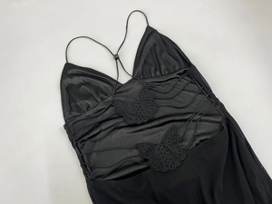 Detail of butterfly lace appliques and adjustable strap on a black satin slip dress
