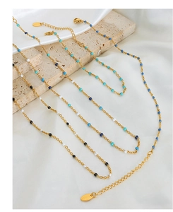 Detailansicht goldener Boho-Halsketten mit bunten Perlen auf weißem Seidenhintergrund