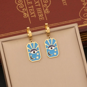 Detail of celestial gold earrings with blue enamel eye, crescent moon, and stars pattern