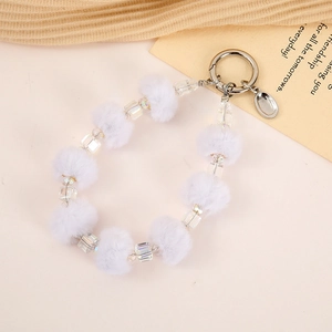 Detail of white faux fur pompom and clear faceted beads on a silver keychain with ring