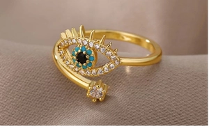 Macro shot of evil eye ring with blue and black crystals on champagne satin background