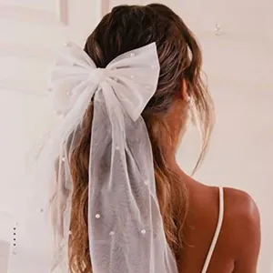 Detail of white bridal veil with soft tulle, elegant bow, and faux pearls decoration