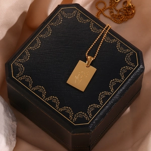 Close-up of 18K gold square pendant with hand and star pattern on black jewelry box