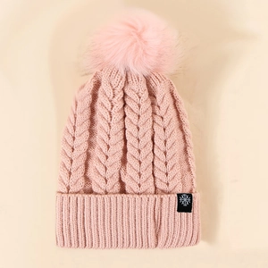 Close-up of pink knit beanie featuring snowflake label and fluffy pom-pom detail
