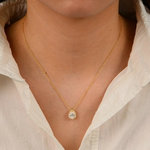 Elegant gold pear-shaped zircon necklace on woman neck with minimalist teardrop pendant
