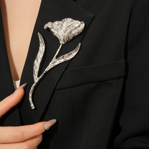 Close-up of a silver tulip flower brooch with metallic texture on a dark blazer lapel
