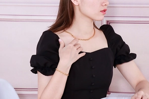 Set aus goldener Edelstahl-Halskette und Armband, getragen vor rosa Hintergrund