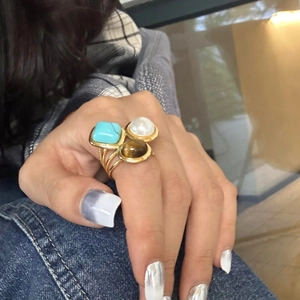 Detailed view of bohemian gold ring featuring turquoise, pearl and tiger eye gemstones