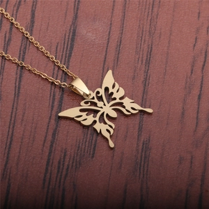 Elegante goldene Halskette aus Edelstahl mit Schmetterlingsanhänger auf dunklem Holzgrund