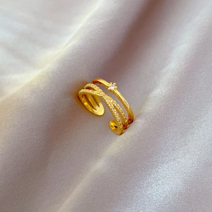 Close-up of gold plated multi-layer open ring with zircon flowers on purple silk fabric