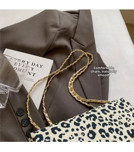 Close-up of leopard print shoulder bag with gold chain strap on a brown blazer backdrop