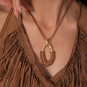 Detail of bohemian gold hollow pendant with brown velvet cord winding on a model