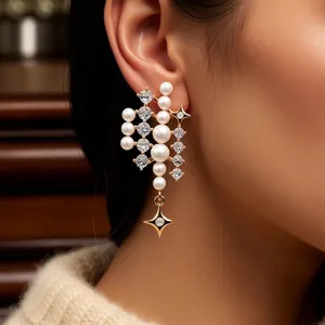 Eleganti orecchini pendenti dorati con perle, strass e ciondolo a stella su una modella
