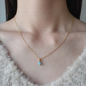 Dettaglio della collana a catena dorata con pendente tondo in pietra blu