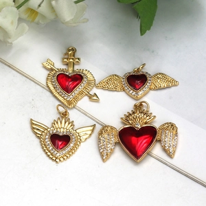 Detailed macro view of gold heart pendants with red enamel and sparkling zircon accents