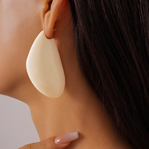Gros plan d'une boucle d'oreille goutte irrégulière en résine crème sur un mannequin