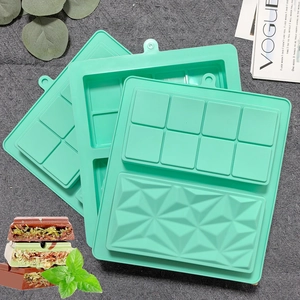 Mint green silicone chocolate bar molds with square and diamond textures on gray fabric