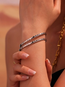 Close-up of dual silver bamboo textured stainless steel bangles worn by a model
