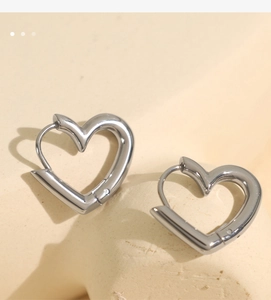 Macro shot of silver heart-shaped hollow earrings with metallic luster on textured stone