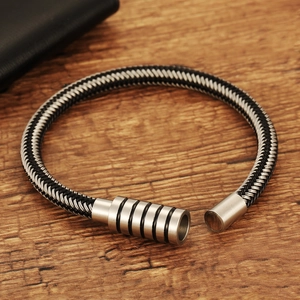 Minimalist black and white woven rope bracelet with cylindrical magnetic clasp on wood