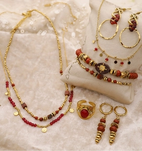 Détails d'une parure de bijoux vintage dorés avec perles marron rouge et bagues