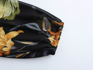 Dettaglio macro dei polsini elastici su un abito in chiffon a motivi floreali vivaci
