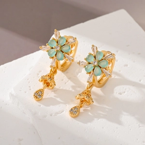Close-up of gold flower earrings with mint green petals and cubic zirconia accents