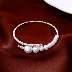 Detailed view of silver bypass bracelet with sparkling rhinestones and gradient white pearls