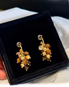 Detail of tiger eye bead earrings with golden beads and zircon on black velvet