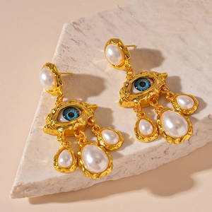 Détail macro de boucles d'oreilles œil porte-bonheur dorées avec perles et métal martelé