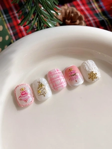 Detailed view of pink and white Christmas press-on nails with 3D snowflakes and gold trees